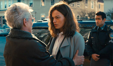A still from 'Ella McCay'. An older woman grasps the arms of a younger smartly dressed woman, who looks at her in confusion. There is a policeman behind them