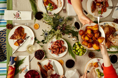 Wide shot of a festive dining table set-up with a whole turkey, sides and guests