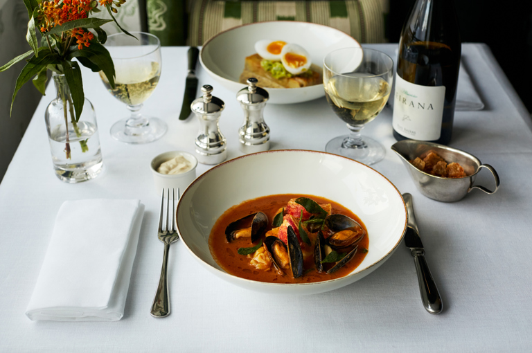 Close up shot of a main course of shellfish stew in a shallow bowl on a table at The Potting Shed
