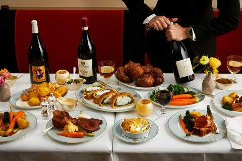 The Long Lunch at Ham Yard. A large table with three magnums of wine, sharing plates of meat and sides of potatoes, vegetables and cauliflower cheese
