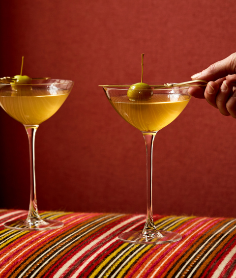 An image of two vodka based martini cocktails, sitting on stripy furniture. 