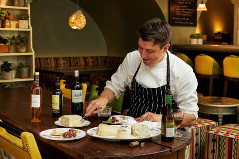 A image of Joe Fox at a table with multiple different plates with cheeses and wine at The Potting Shed, Dorset Square Hotel.