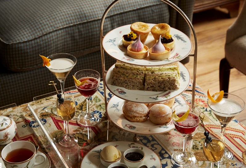An afternoon tea setup with a sofa next to the table.