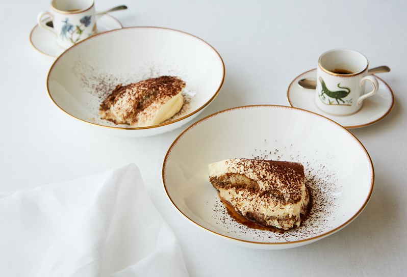 Two portions of Tiramisu with two espresso cups and saucers