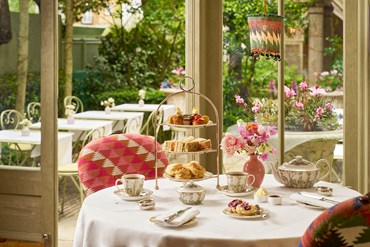 Afternoon tea displayed on a table in the Orangery looking on to the garden at Number Sixteen hotel. The fine bone china is Mythical Creatures by Kit Kemp for Wedgwood along side a 3 tier cake stand, sandwiches and scones.
