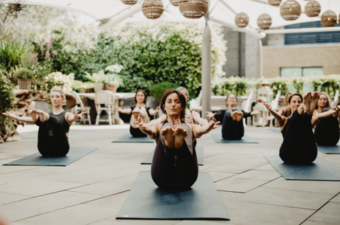 An image of Equinox instructors doing a yoga class to promote the series of classes hosted by Equinox on Ham Yard Hotels Roof Terrace.