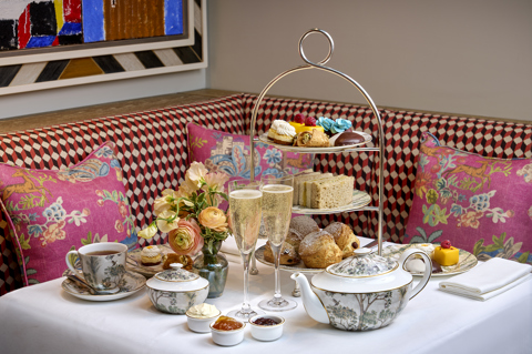 A wide shot of the New York Afternoon Tea at Warren Street Bar: there is a stand of scones, sandwiches and pastries, served with champagne