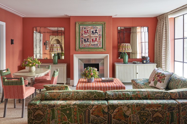 A wide shot of the living area of the Deluxe Two Bedroom Suite Room 5 at Ham Yard Hotel. The image shows the back of a 'L shaped' sofa on the right hand side, pointing towards the fire place. On the left the dining table with 4 chairs around 