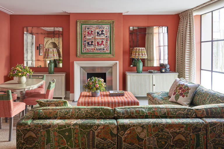 A wide shot of the living area of the Deluxe Two Bedroom Suite Room 5 at Ham Yard Hotel. The image shows the back of a 'L shaped' sofa on the right hand side, pointing towards the fire place. On the left the dining table with 4 chairs around