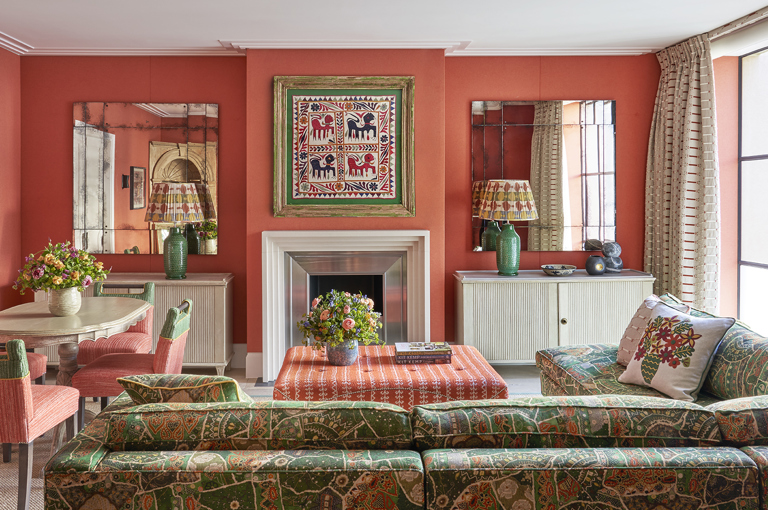 A wide shot of the living area of the Deluxe Two Bedroom Suite Room 5 at Ham Yard Hotel. The image shows the back of a 'L shaped' sofa on the right hand side, pointing towards the fire place. On the left the dining table with 4 chairs around
