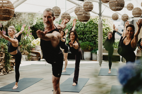 An image of Equinox instructors doing a yoga class to promote the series of classes hosted by Equinox on Ham Yard Hotels Roof Terrace.