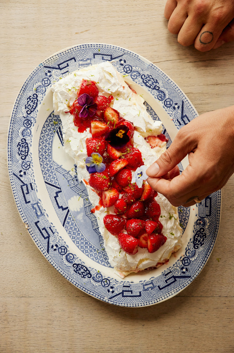 A close-up portrait shot of the strawberry and lime meringue roulade served on an oval dish