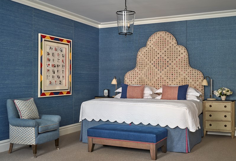 Bedroom photo of Room 109 Connecting Junior Suite with a Bed, two bed side table and an arm chair. The room is blue themed in general.