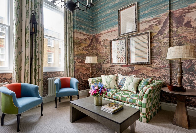 An image of two blue and red rub chairs in front of a wooden staircase and nautical wallpaper in the loft suite at Charlotte Street Hotel