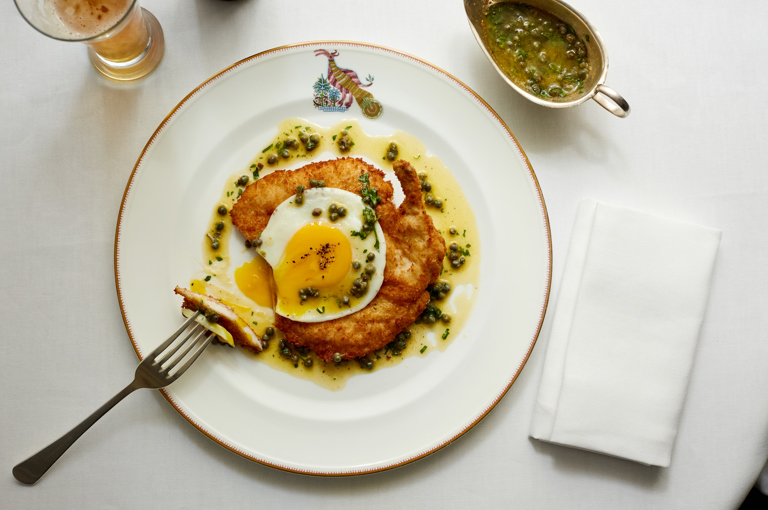A main course of chicken schnitzel and fried egg with a section cut out, shot from above at Brumus