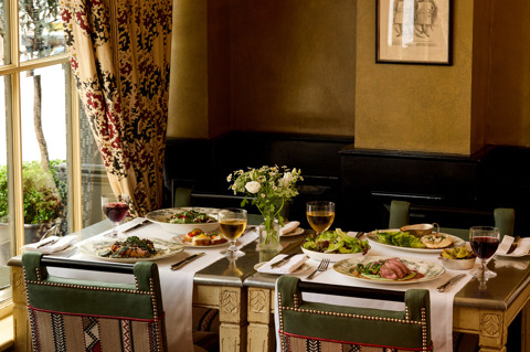 An image to promote Brasserie Max’s À La Carte menu at Covent Garden Hotel. The image shows a variety of dishes on the rectangular table and glasses of wine.