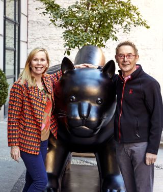 This image shows Kit and Tim Kemp standing next the Botero Cat statue that sits outside Warren Street Hotel in New York. Kit stands on the left smiling with Tim on the right of the statue smiling.