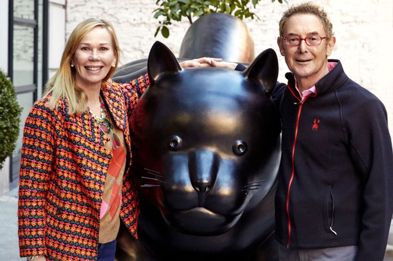 This image shows Kit and Tim Kemp standing next the Botero Cat statue that sits outside Warren Street Hotel in New York. Kit stands on the left smiling with Tim on the right of the statue smiling.