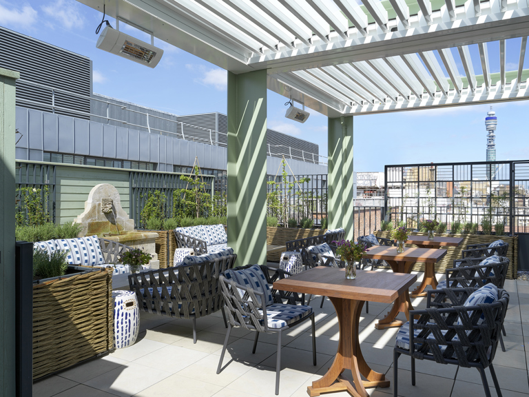 A wide shot of the view of the Roof Terrace top floor featuring lounge seating, occasional tables and views over the Soho skyline at 9-11 Richmond Buildings