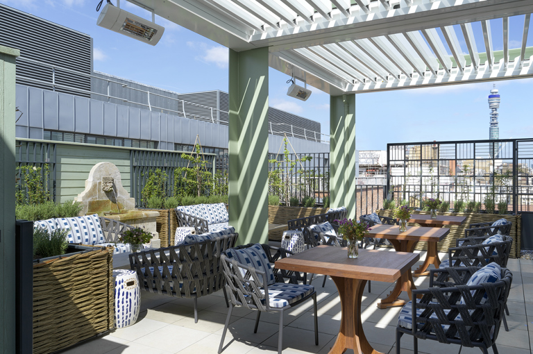 A wide shot of the view of the Roof Terrace top floor featuring lounge seating, occasional tables and views over the Soho skyline at 9-11 Richmond Buildings