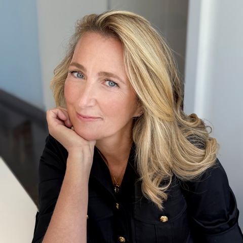 An headshot image of the author Belle Burden to promote her new book Strangers. she can be seen leaning on her right hand looking directly into the camera. 