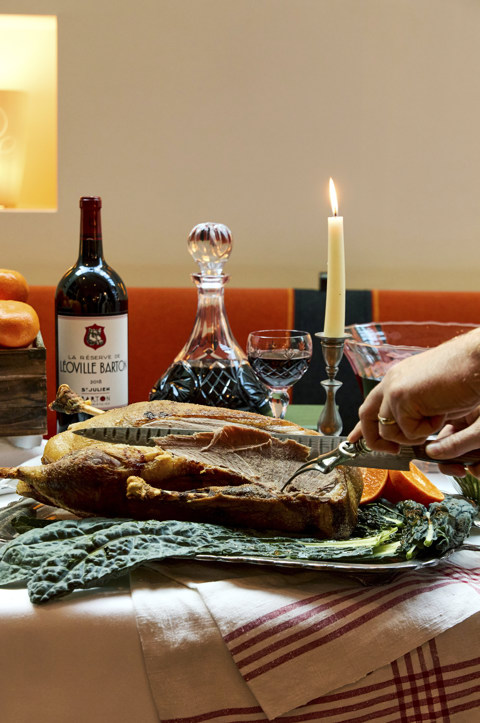 A close up image of a someone cutting into a roast duck surrounded by oranges to promote The Great Christmas Feast at Ham Yard, Ham Yard, Hotel.