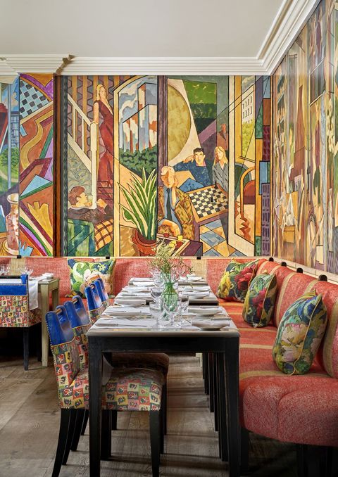 Oscar Restaurant with a colourful mural covering the walls, tables set up with with table cloths, cultery and glasses