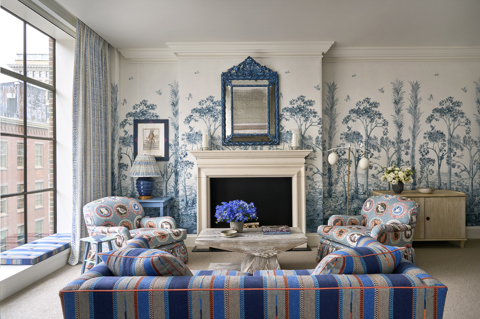 Wide living room shot of room 609, a Luxury One Bedroom Suite at Crosby Street Hotel. The image shows the back of a sofa with a coffee table and two armchairs in front of a fireplace