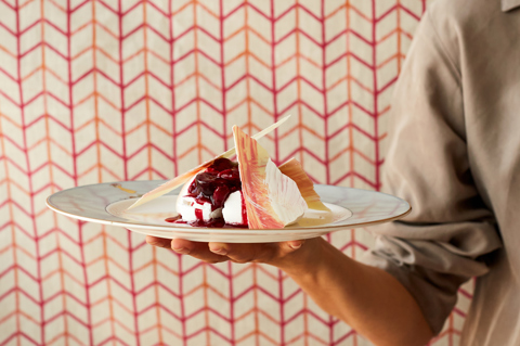 A plate of pavlova being carried by a chef, who is partially in view