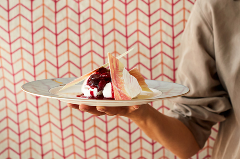 A plate of pavlova being carried by a chef, who is partially in view