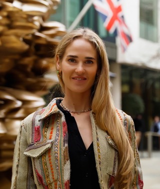 A close up shot of Firmdale Art Ambassador and Design Director Willow Kemp standing in front of the Tony Cragg sculpture in the courtyard at Ham Yard Hotel