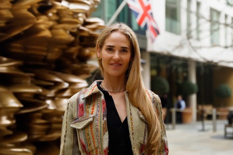 A close up shot of Firmdale Art Ambassador and Design Director Willow Kemp standing in front of the Tony Cragg sculpture in the courtyard at Ham Yard Hotel