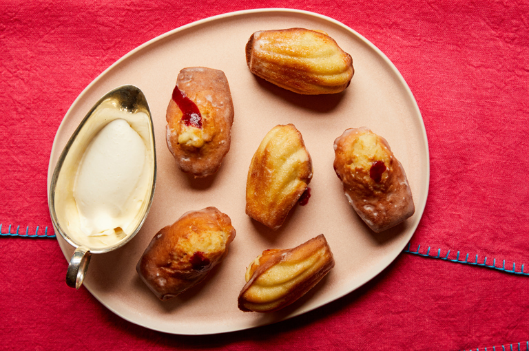 A plate of madeleines with a side of whipped cream in a jug at Brasserie Max