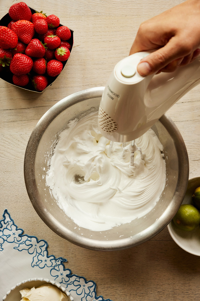 A close-up portrait shot of the egg whites being whisked to make strawberry and lime meringue roulade being served onto a smaller plate