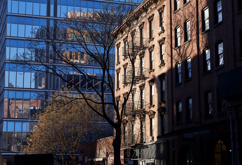 A redbrick warehouse building sits next to a modern glass and concrete building in Tribeca, New York