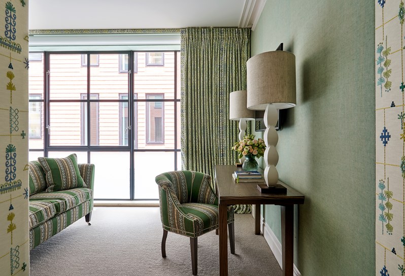 A room at Ham Yard Hotel with a floor-to-ceiling crittal-style windows and a dressing table and chair