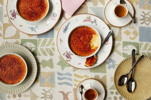 Close up shot of Creme Brulee taken from above, on a tablecloth with a coloured design 