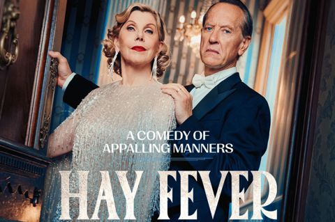 A promotional poster for Hay Fever play at Wyndham's Theatre. Christine Baranski stands dressed in a jewelled tassel dressed and Richard E. Grant stands behind her dressed in a suit and white bow tie