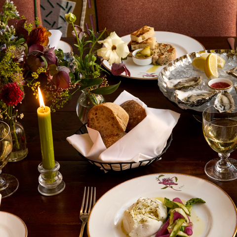 A close-up wide shot of private dining in the Dora Carrington Room at Charlotte Street Hotel: there are various lunch dishes being served including oysters and burrata