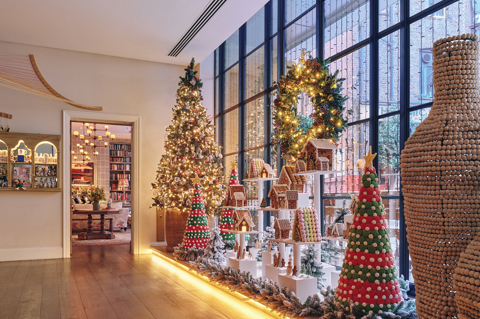 A landscape image of the Ham Yard Hotel lobby decorated for Christmas, there is a Christmas tree in the background and a gingerbread village in the centre.