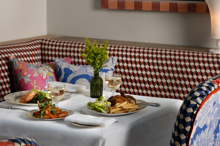 A wide angle shot of a table set up for dinner in Warren Street Bar. There are dishes of Lancaster chicken and grilled salmon, with white wine pairings
