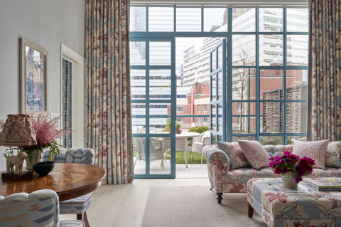 A wide shot of the living room with doors opening onto a terrace in Two Bedroom Warren Terrace Suite at Warren Street Hotel