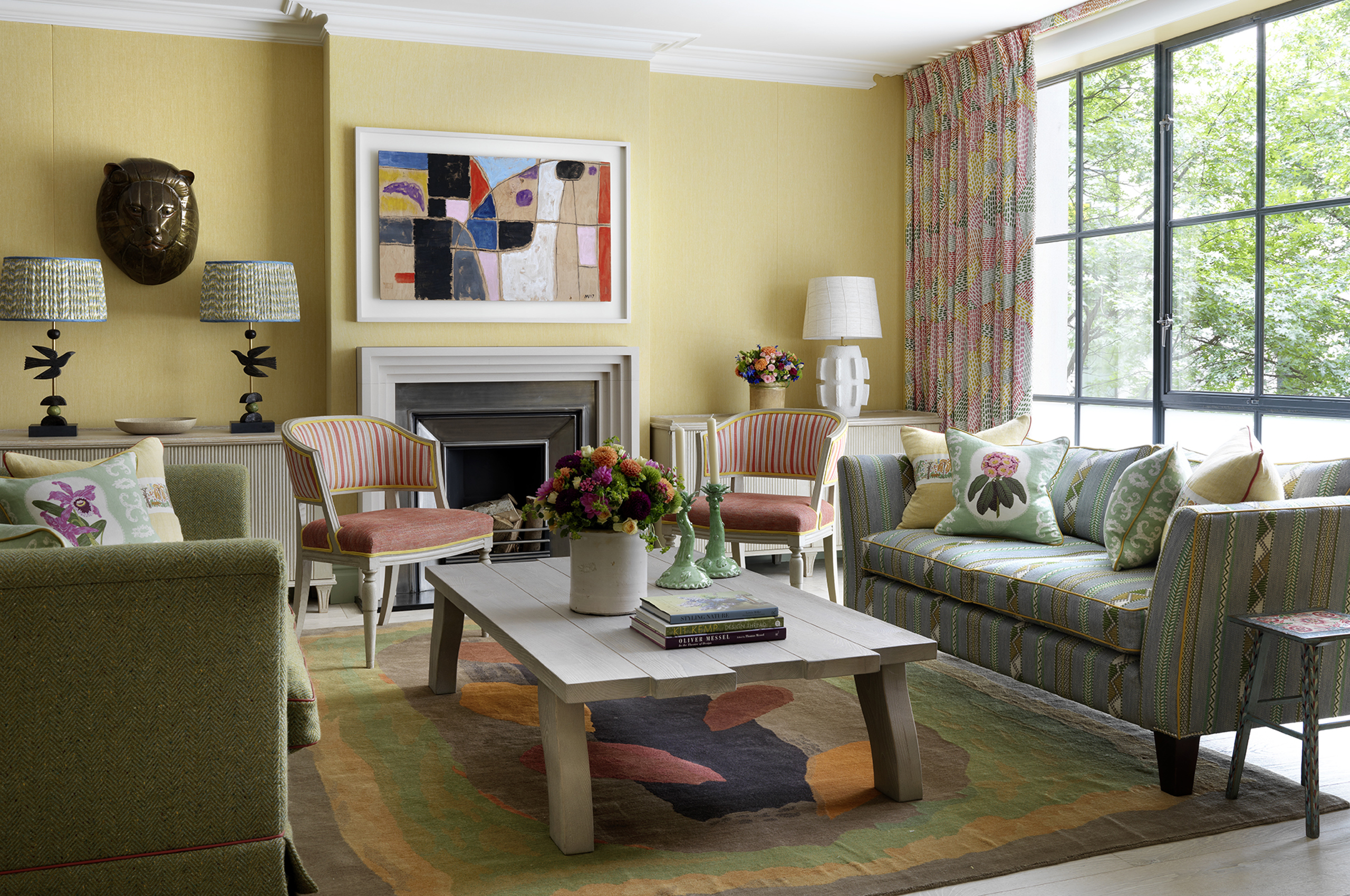Elegant living room with yellow walls, fireplace, and striped chairs
