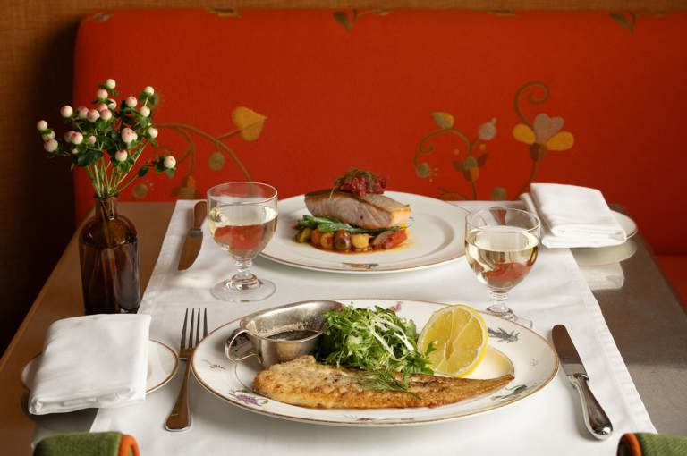 A close-up portrait shot of a table set up for dinner at The Crosby Bar: there are dishes of dover sole and salmon