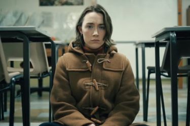 This image shows actress Saoirse Ronan sitting on the floor looking sadly into the camera, it is a still from the film Bad Apples.