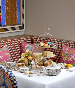 A portrait shot of the New York Afternoon Tea at Warren Street Bar: there is a stand of scones, sandwiches and pastries, served with champagne