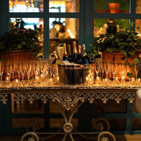 A table laid with Champagne glasses and tealights. In the middle there is an ice bucket full of bottles of Champagne