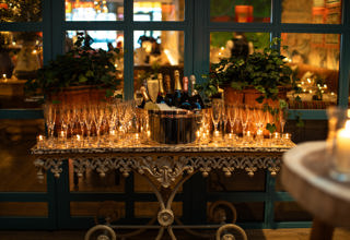 A table laid with Champagne glasses and tealights. In the middle there is an ice bucket full of bottles of Champagne