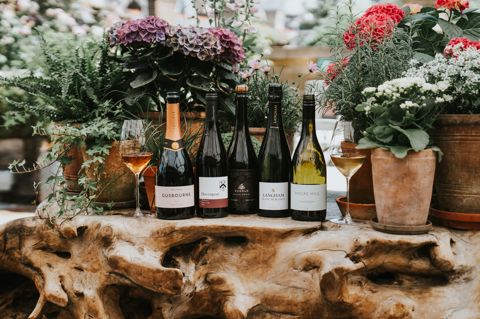 A wide shot of a selection of wines against a floral backdrop, on the roof terrace at Ham Yard Hotel