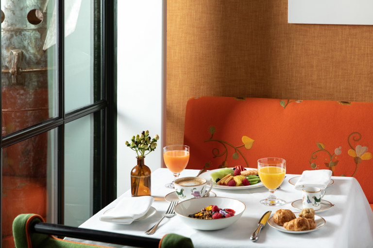 A table set up for breakfast at The Crosby Bar. Dishes of granola, a fruit plate and pastries on the table